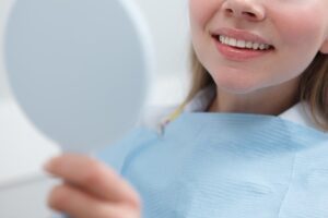 Close-up of a dental patient examining her teeth in a hand mirror